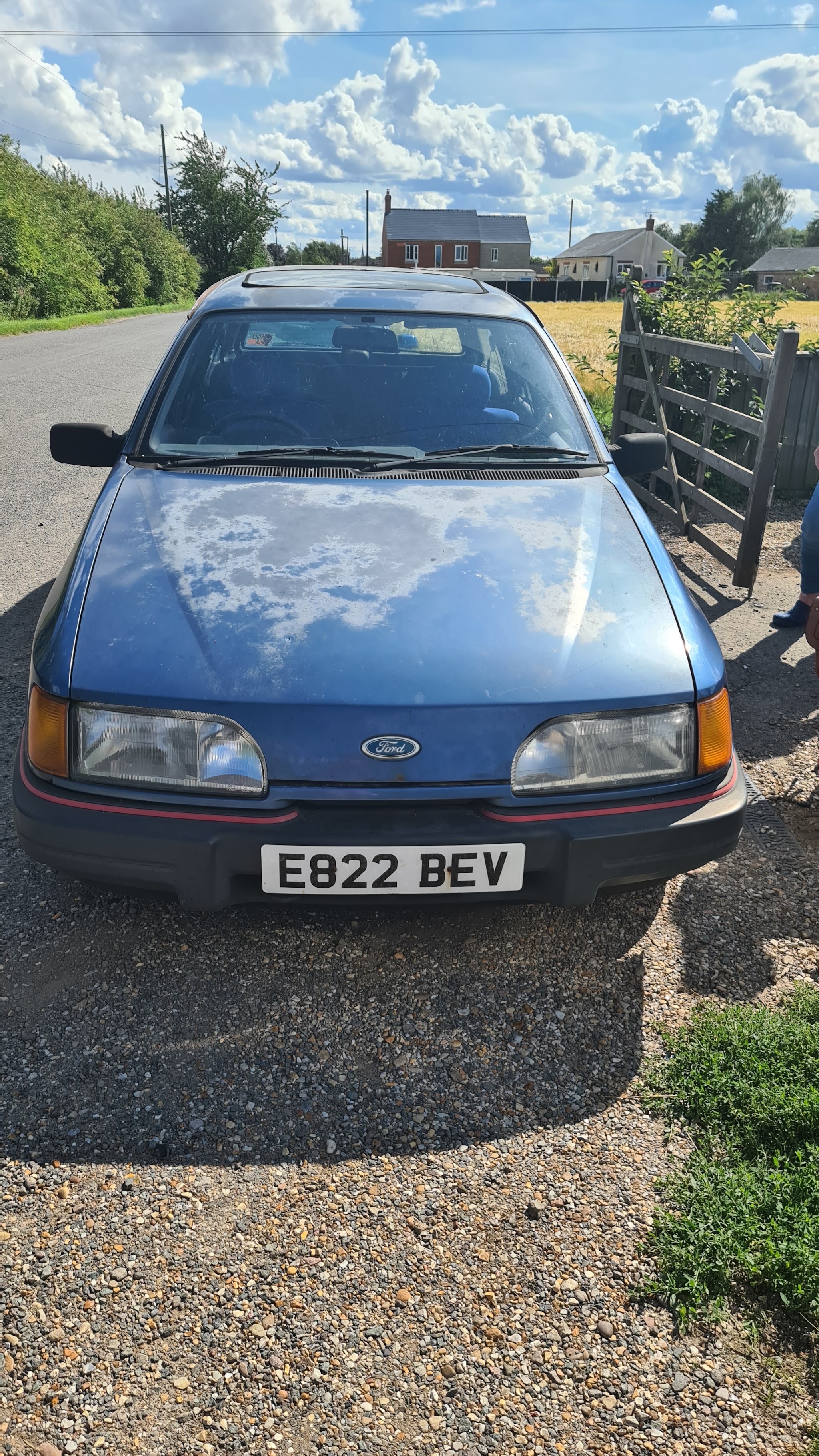 Classic blue Ford parked on a gravel drive