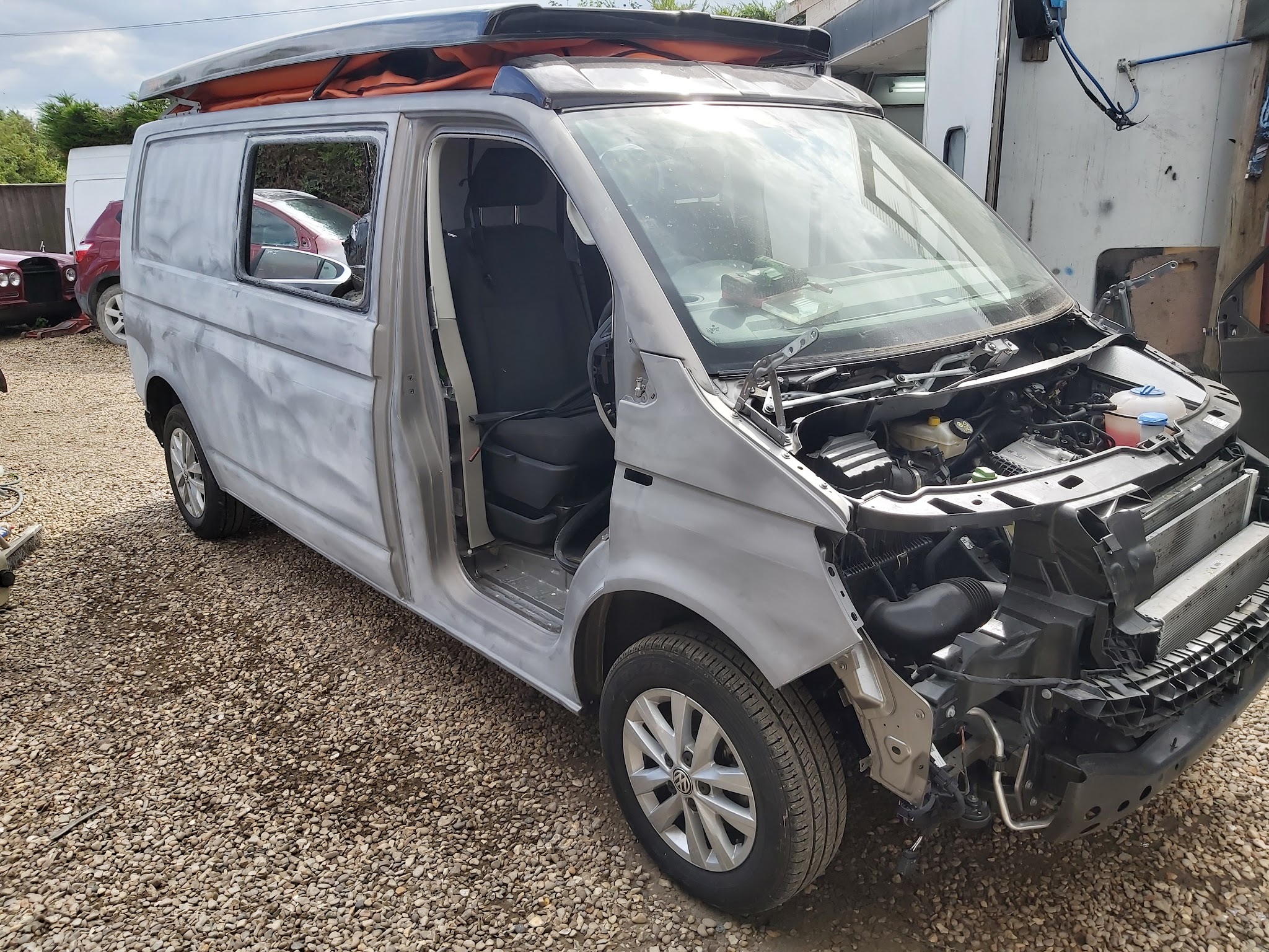 Silver VW van with its front end stripped back for accident repair