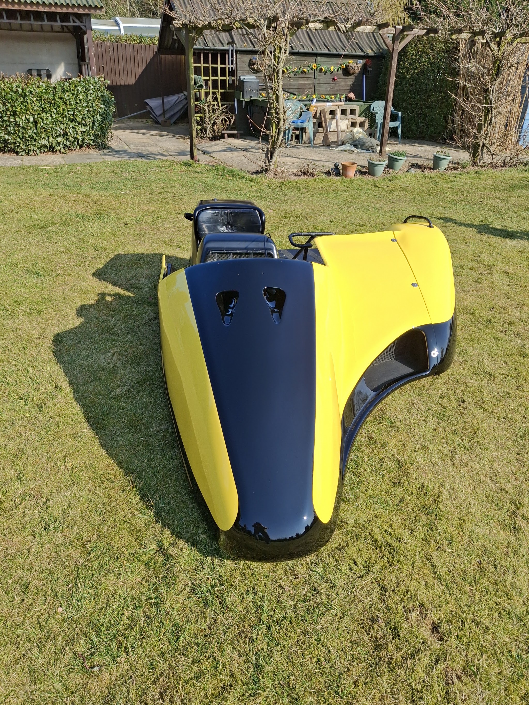 Freshly painted yellow and navy fairing drying on a lawn